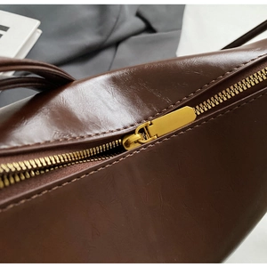 Detailed close-up of premium dark brown leather bucket bag with gold metal zipper