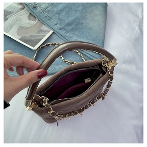 Detail view of the brown suede handbag showing purple lining and secure zipper closure