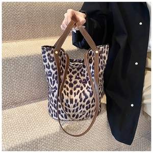 Detail of leopard print bucket bag with double brown handles on textured stairs