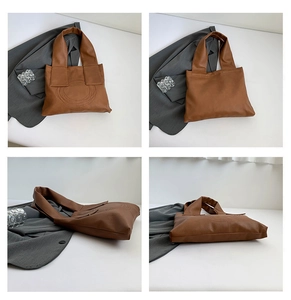 Detail view of brown tote bag showing litchi texture and elegant curved stitching