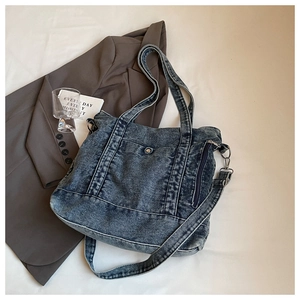 Detail of blue denim tote bag with buckle pocket and adjustable shoulder strap