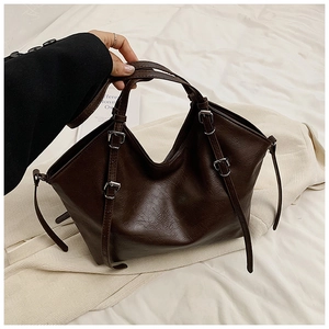 Detail of dark brown faux leather tote with silver metal buckles and decorative straps