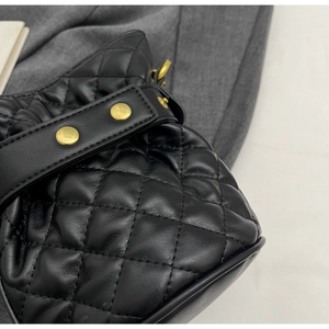 Detailed close-up of black quilted leather bucket bag with golden studded strap
