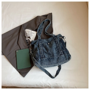 Detail of vintage washed denim tote bag with functional multi-pockets and dual straps