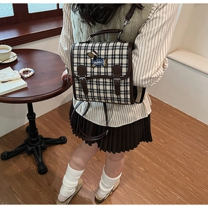 Detail view of retro plaid backpack featuring dachshund embroidery and brown leather straps