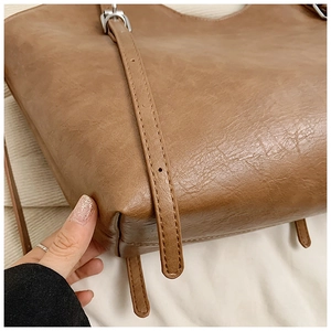 Close-up of camel tote bag base with premium lychee texture and silver metal buckle