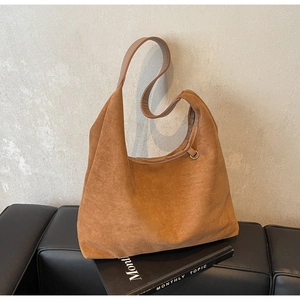 Détail du sac hobo en daim marron montrant la texture mate et l'anneau métallique