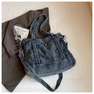 Detail of washed denim tote bag with metal buttons and adjustable crossbody strap