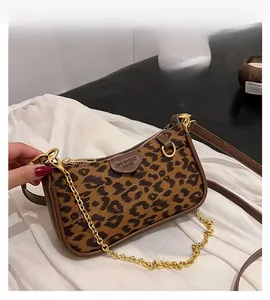 Close-up of leopard print baguette bag with gold chain and dual leather straps