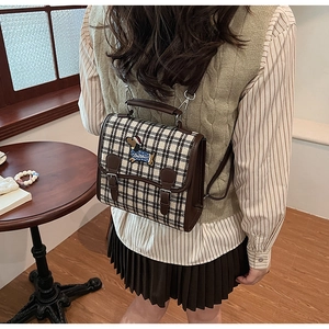 Detailed view of vintage plaid backpack with embroidery on a classic flap bag design