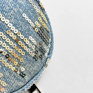 Detailed close-up of light blue washed denim fabric with decorative metallic sequins