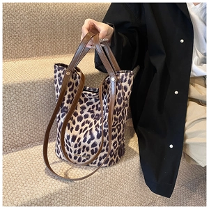 Close-up of leopard print bucket bag with brown leather straps and metal brand logo