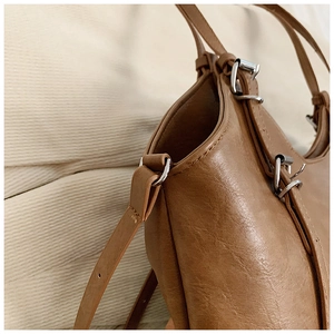 Detailed close-up of brown leather tote bag with silver D-ring and neat stitching