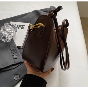 Detail view of dark coffee bucket bag showing matte leather texture and gold hardware