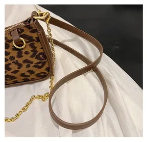 Close-up of leopard print baguette bag featuring golden chain and brown leather strap