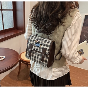 Detail of vintage plaid backpack with puppy embroidery patch and leather strap buckles
