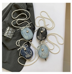 Détail de mini sacs en jean avec paillettes, bandoulière perle et breloque en cœur