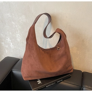 Détail macro de la texture en daim marron et de l'anneau métallique du sac hobo