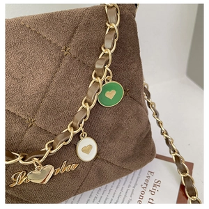 Close-up of brown suede quilted handbag with gold chain strap and heart charms