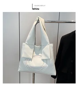 Detail of white tote bag featuring lychee texture and circular stitching on wide strap