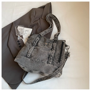 Detailed view of washed denim tote bag with metal button pocket and zipper accents