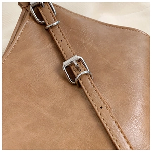 Detail of adjustable brown leather shoulder strap with silver metal buckle and fine stitching