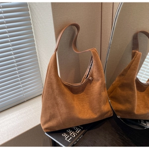 Gros plan détaillé montrant la texture douce du daim et le fini brun caramel riche du sac