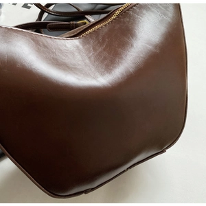 Detailed close-up of dark brown vintage faux leather texture and bronze zipper on bucket bag