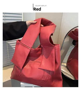 Detail of red leather tote bag showing litchi texture and unique knotted shoulder strap