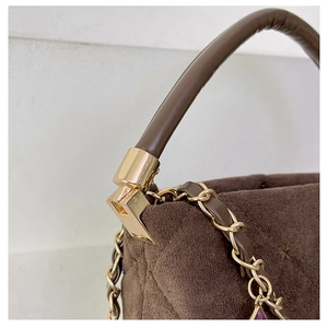 Detail of dark brown suede handbag with quilted stitching and gold chain strap