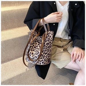 Detail of large leopard print bucket bag with brown leather handles on stairs