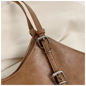 Close-up of brown leather bag showing vintage texture and silver adjustable buckles
