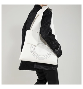 Close-up of minimalist white tote bag with black artistic lines on textured leather