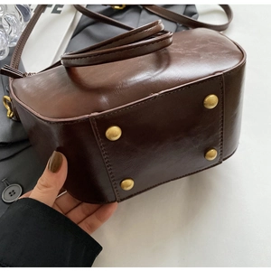 Detailed view of the dark brown retro leather bag bottom with golden metal feet