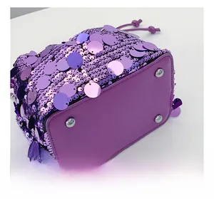 Dettaglio della borsa a secchiello in paillettes viola con quattro piedini in metallo
