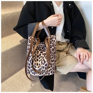 Detail of leopard print suede bucket bag with brown leather handles on stairs