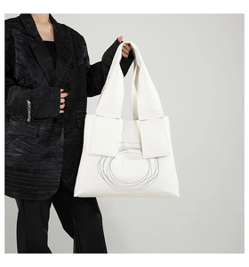 Detailed view of white leather tote bag with black geometric concentric circles