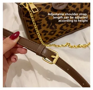 Detailed close-up of adjustable brown leather shoulder strap with gold buckle on leopard bag