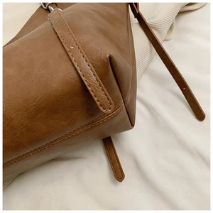 Detail of fine stitching and brown leather texture on the elegant tote bag with strap