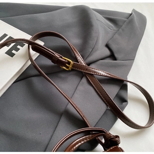 Detail of adjustable brown leather shoulder strap with gold buckle and fine stitching