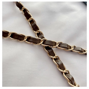 Detailed close-up of the woven metal and brown leather chain strap on a stylish handbag