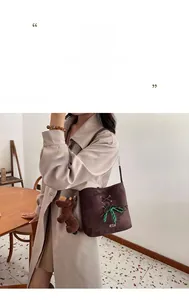 Detailed macro view of dark brown suede bucket bag with green lacing and puppy charm