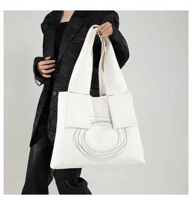 Detail of white lychee textured tote bag featuring artistic black spiral embroidery