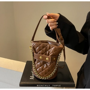 Detail of brown quilted bucket bag with gold chain and diamond lattice pattern