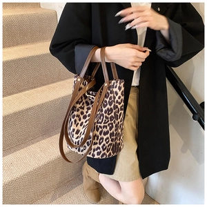 Detail of leopard print tote bag with brown leather handles and adjustable shoulder strap
