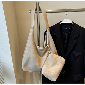 Détail du sac cabas en daim beige avec pochette zippée assortie sur un cintre