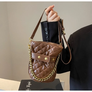 Detail of mini quilted bucket bag in dark brown with gold chain and diamond stitching