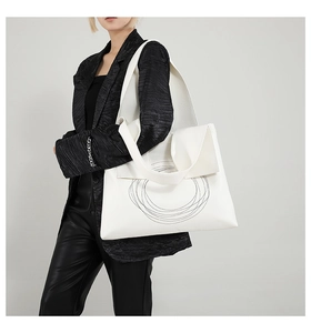 Detail of white tote bag featuring abstract concentric circles and textured leather finish
