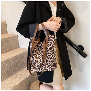 Close-up of leopard print canvas tote bag with brown leather straps on indoor stairs