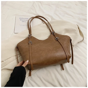 Detail of vintage brown PU leather tote bag with silver buckles and pleated bottom